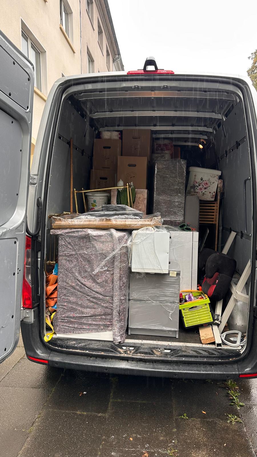 Beladener Möbeltransporter von hinten mit Kartons, folierten Möbeln und Zurrgurt